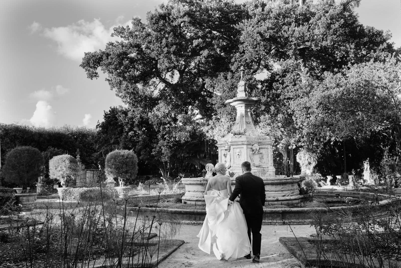 Black and white photograph of a couple walking under trees